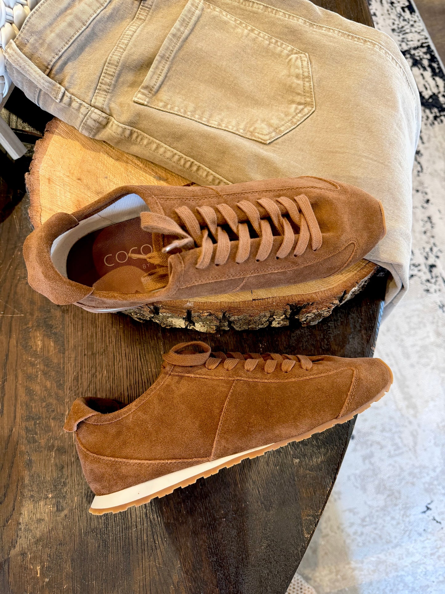 brown suede sneakers against wood background