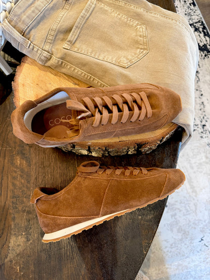 brown suede sneakers against wood background