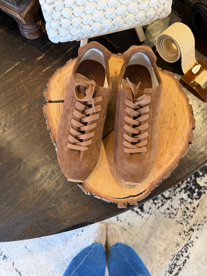 Brown suede sneakers against wooden background