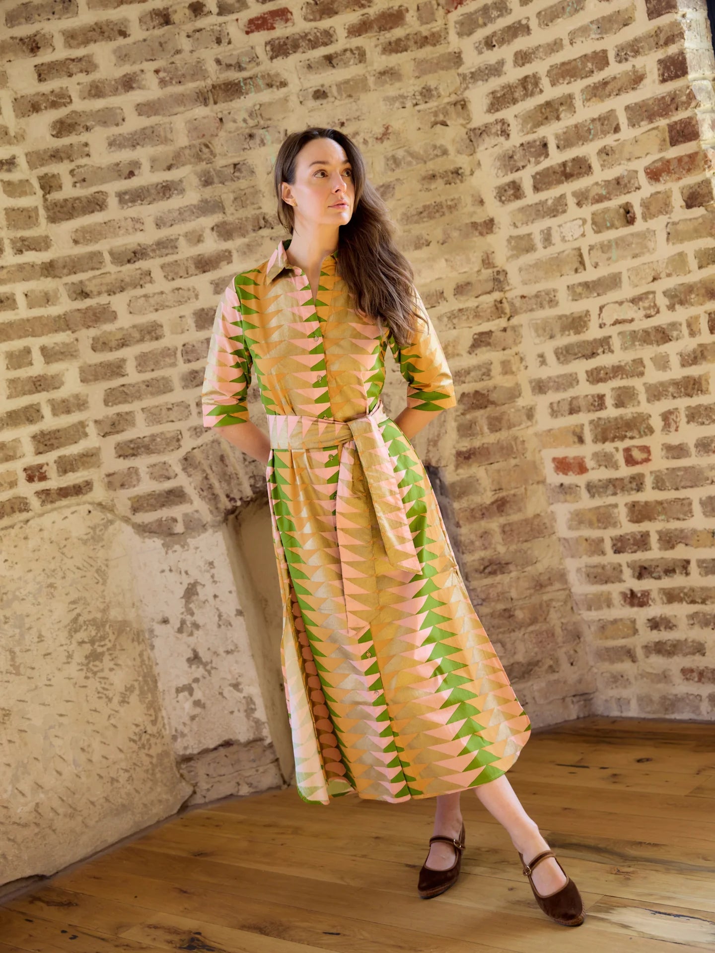 model wearing belted cotton dress against brick background