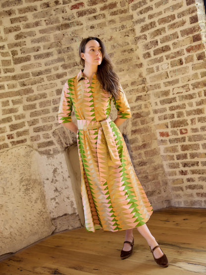 model wearing belted cotton dress against brick background