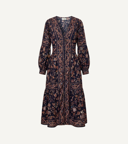 A long-sleeved midi dress with a dark navy blue base and an intricate paisley and floral pattern in brown, beige, and muted orange, shown against a plain off-white background.