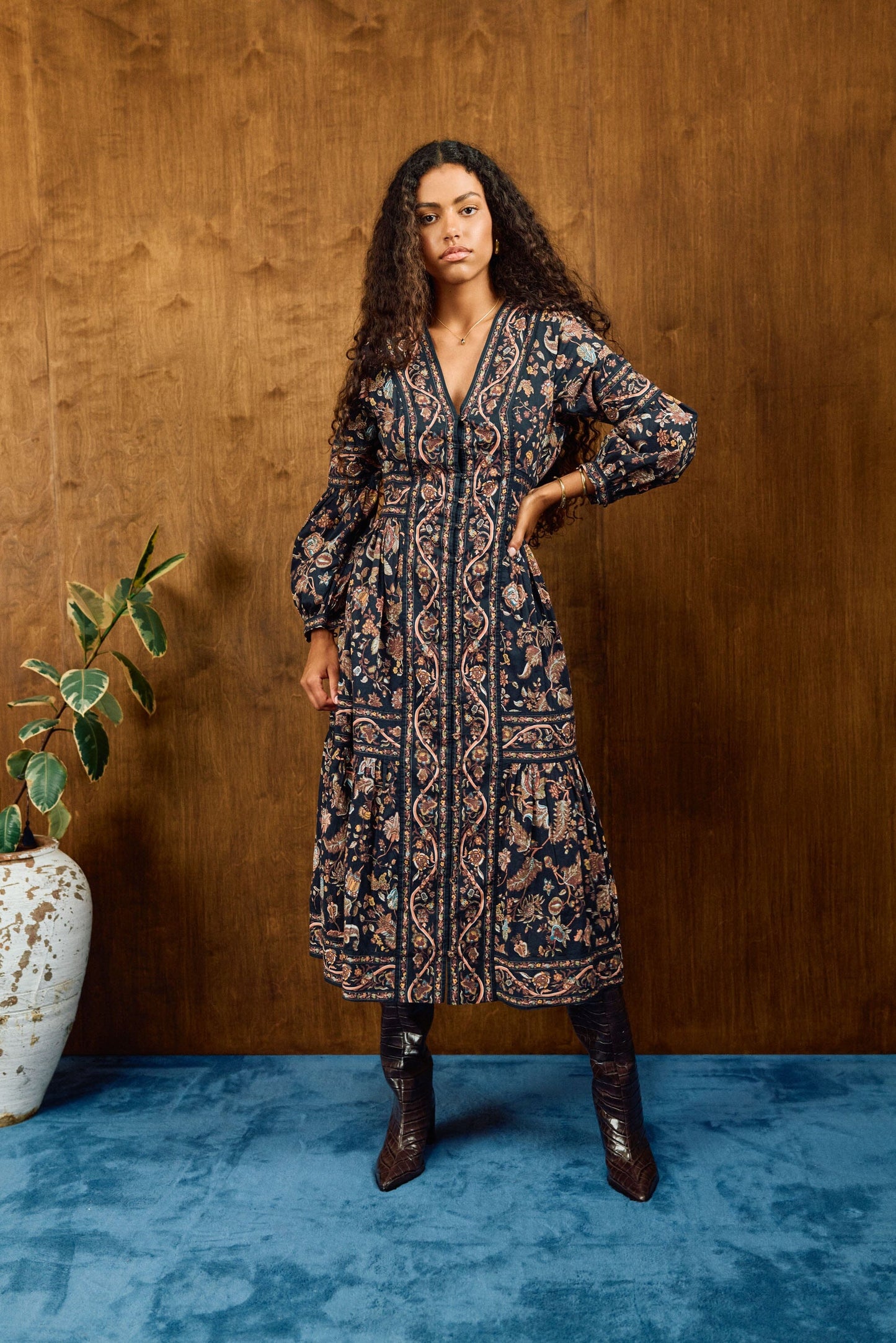 savvy | retail therapy woman stands against a wood background wearing a printed button-up cotton midi dress styled with boots