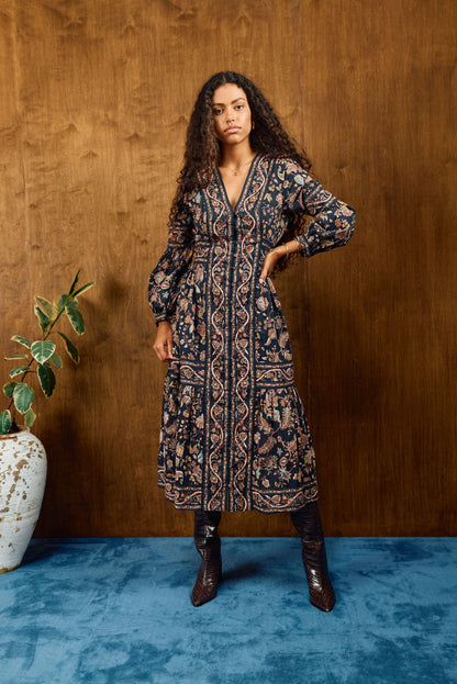 savvy | retail therapy woman stands against a wood background wearing a printed button-up cotton midi dress styled with boots