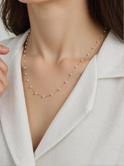savvy | retail therapy close up of a model wearing a dainty pearl necklace   styled with a blazer 