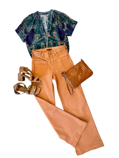 Womens fall outfit flatlay using rust colored denim pant paired with a green blouse and heels